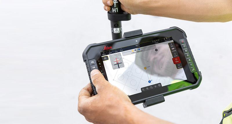 Construction worker holding a black tablet with the Leica iCON trades software, showing points to for efficient layout.